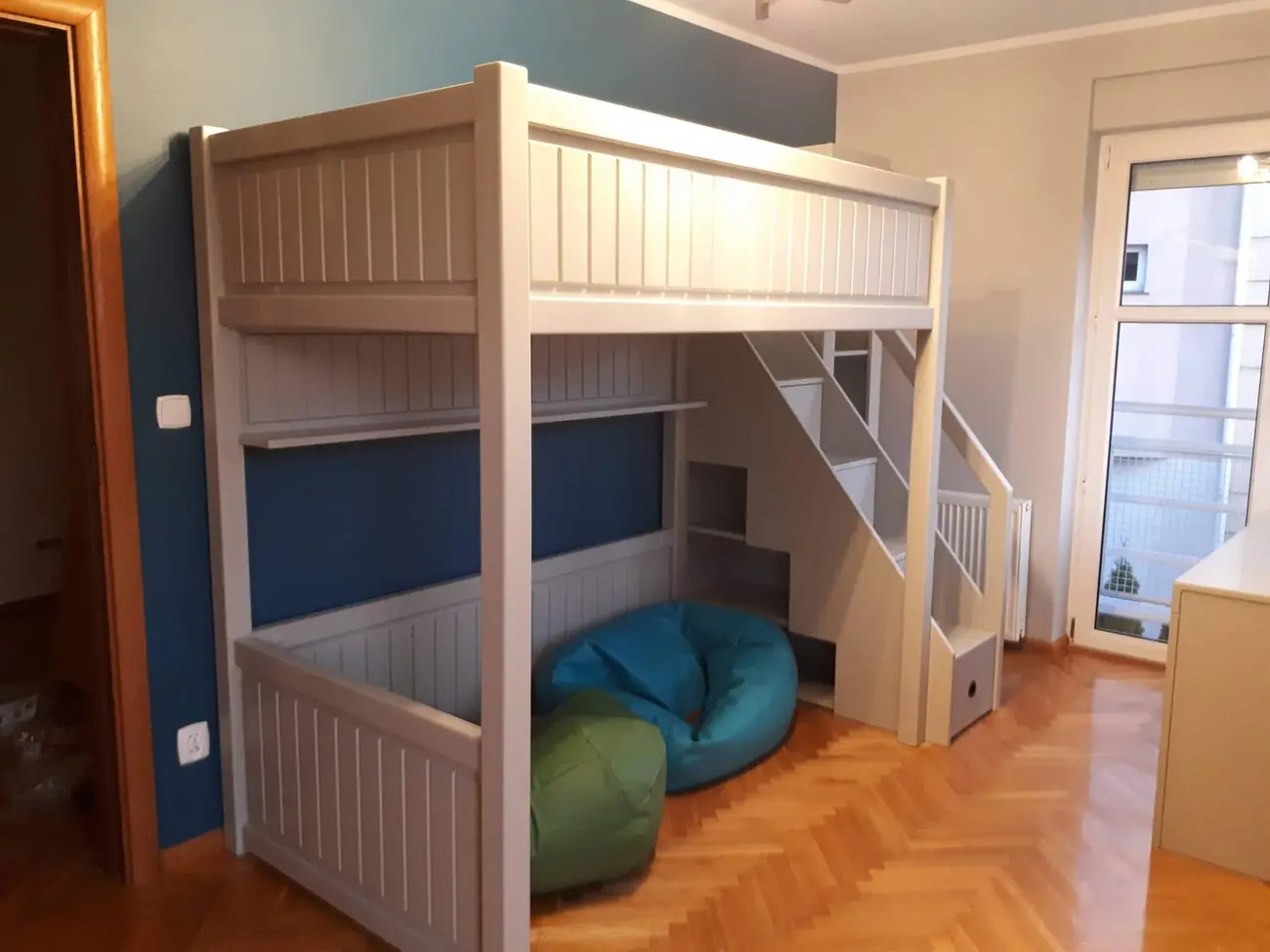 Białe łóżko na antresoli ze schodkami i szufladami